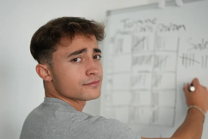 Bastian Holthausen schreibt an ein Whiteboard und schaut über die Schulter